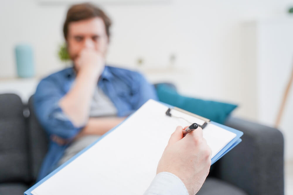 Doctor consulting male patient, working on diagnostic examination of mental illness