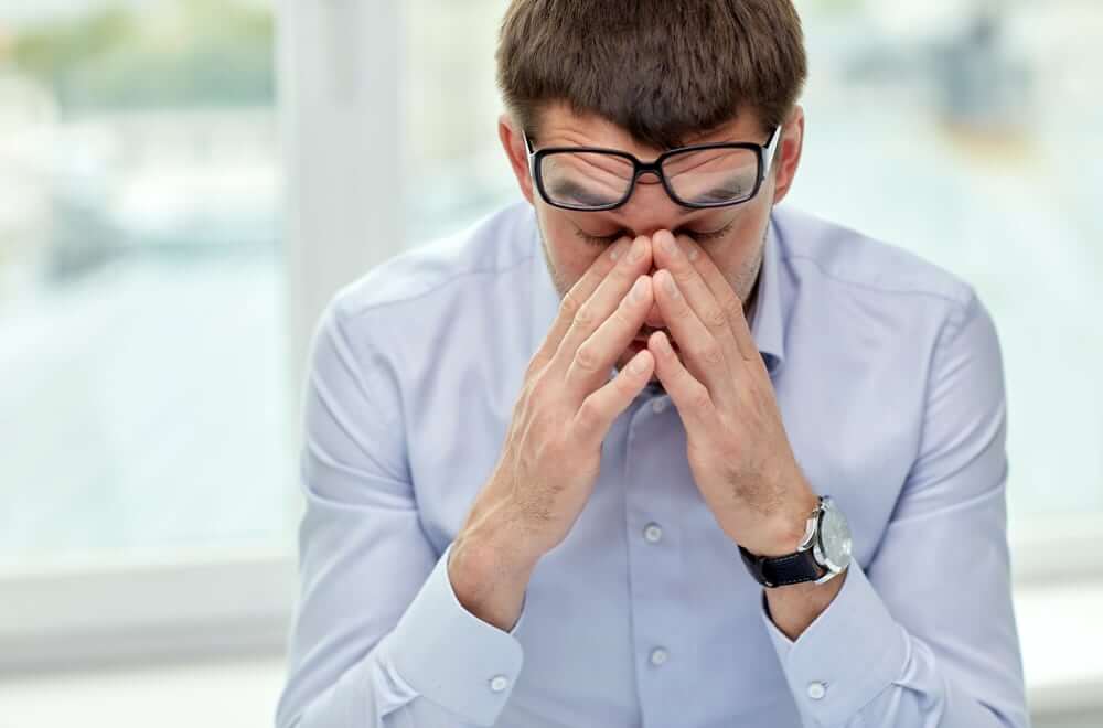 business, people and work concept - tired businessman with eyeglasses in office