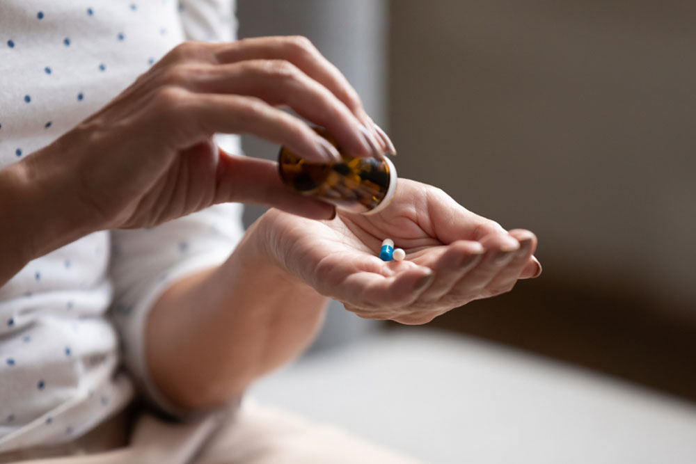 Close up 60s old woman pours out from bottle pills time to take medicaments