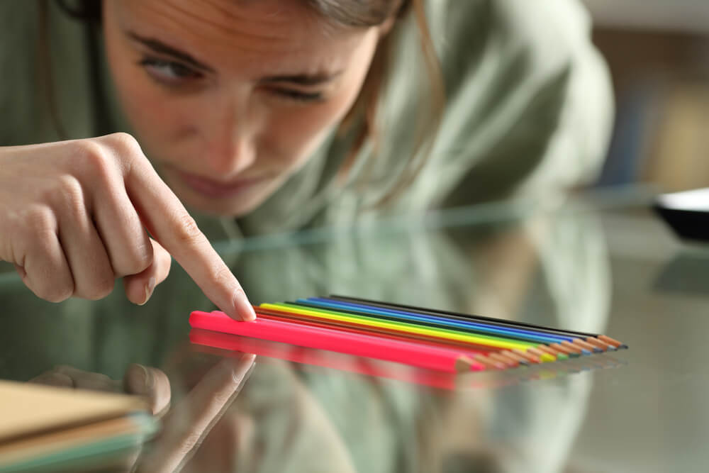 Obsessive compulsive woman aligning up pencils accurately on a glass table